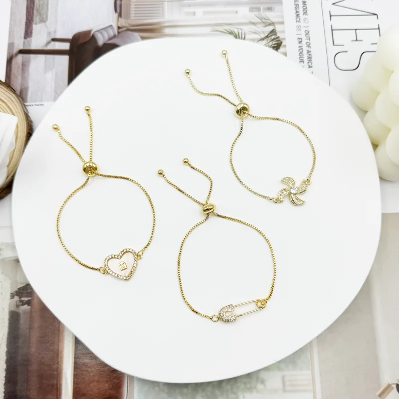 Gold charm adjustable bracelets set with sliding chain designs, heart charm, safety pin charm and pinwheel flower charm styles for wholesale jewelry buyers