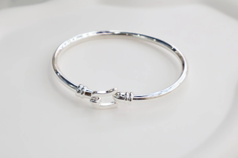 Silver clasp open cuff bracelet with polished metal finish, hook-style clasp detail and minimalist round bangle structure for wholesale jewelry buyers