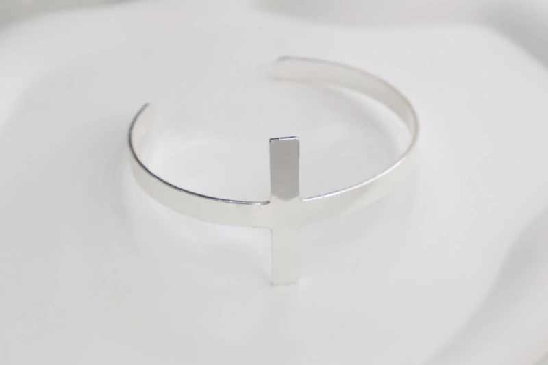 Silver cross open cuff bracelet with polished metal finish, minimalist cross centerpiece and smooth open bangle structure for wholesale jewelry buyers