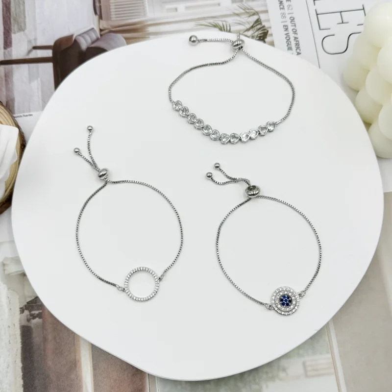 Silver crystal charm sliding bracelets set with rhinestone circle charm, blue evil eye charm and round crystal chain designs for wholesale jewelry buyers