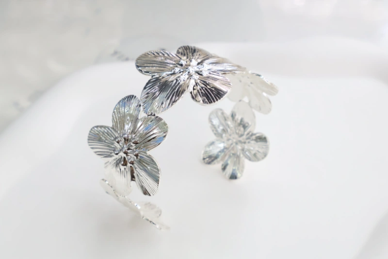 Silver flower open cuff bracelet with polished metal finish, textured floral petal design and statement bangle structure for wholesale jewelry buyers
