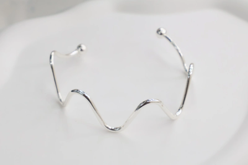 Silver heartbeat open cuff bracelet with polished metal finish, wavy heartbeat line design and round ball ends for wholesale jewelry buyers