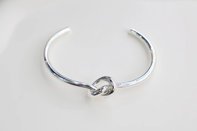 Silver simple knot open cuff bracelet with polished metal finish, minimalist knot centerpiece and smooth open bangle structure for wholesale jewelry buyers