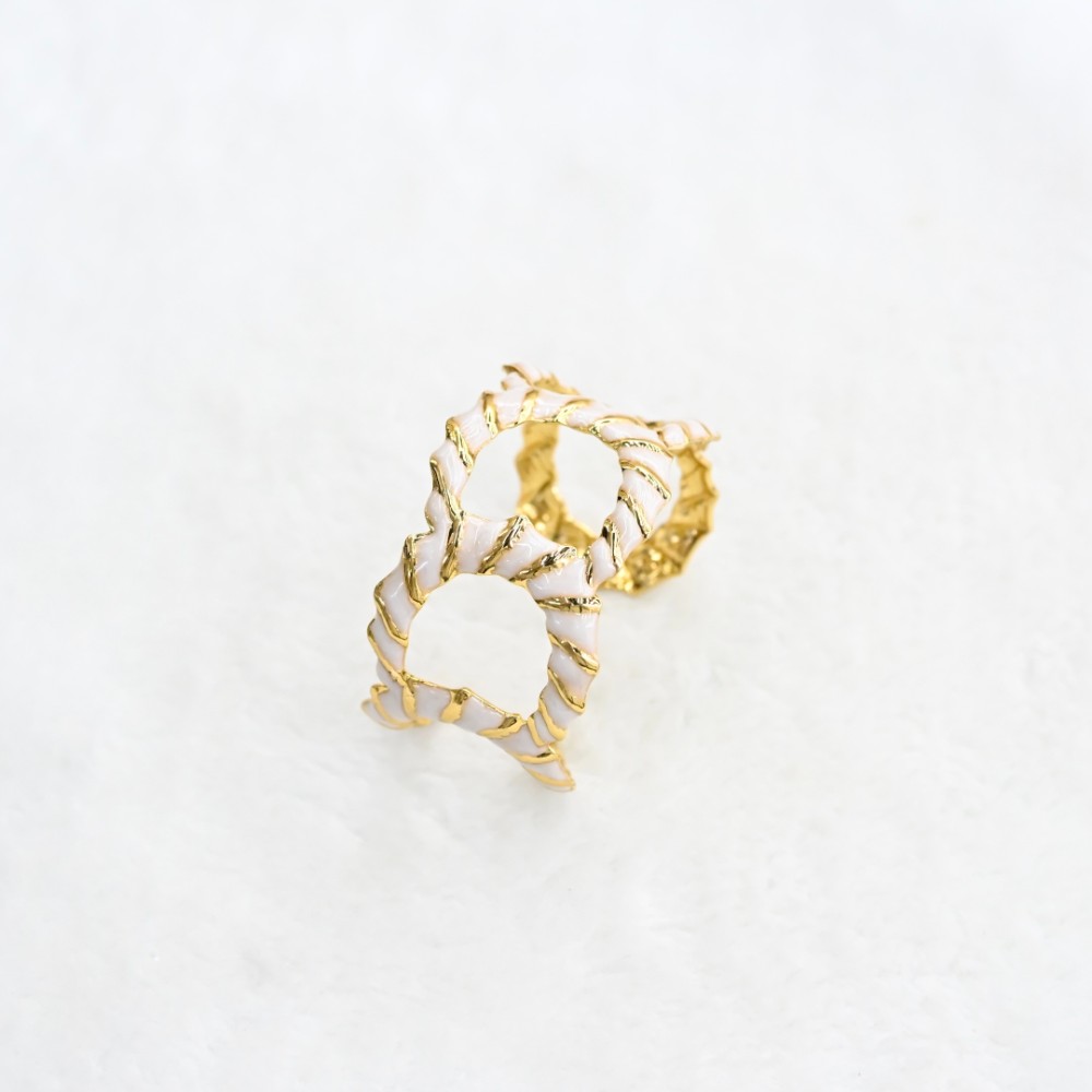 White openwork gold cuff bracelet with hollow oval cutout design, textured gold-tone frame and white enamel-style inlay for wholesale jewelry buyers