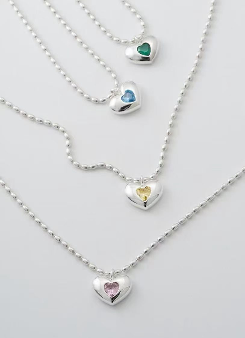 Assorted silver heart stone pendant necklaces with polished heart frames and delicate chain designs for wholesale jewelry buyers