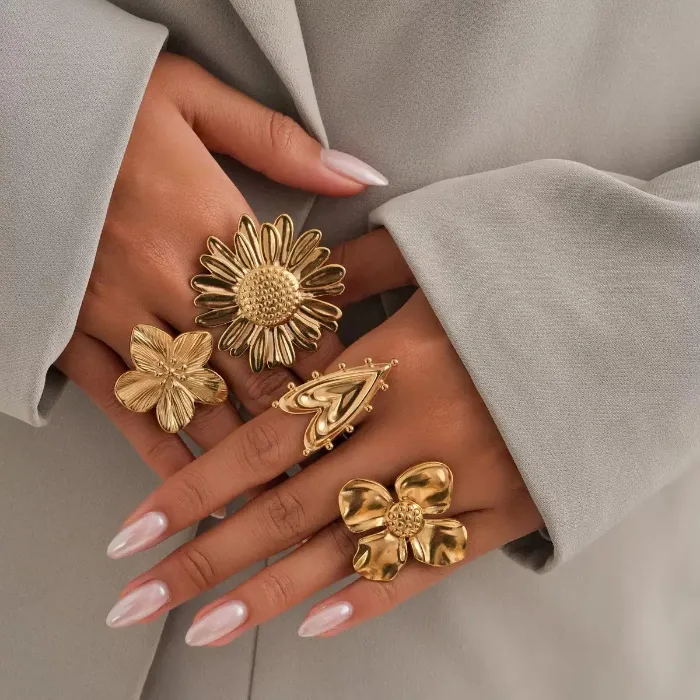 Gold flower statement rings set with oversized floral, sunflower and heart-shaped ring designs shown on hand for wholesale jewelry buyers