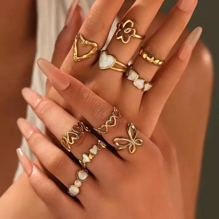 Gold heart butterfly rings set with white shell-style heart, flower and butterfly designs shown on hand for wholesale jewelry buyers