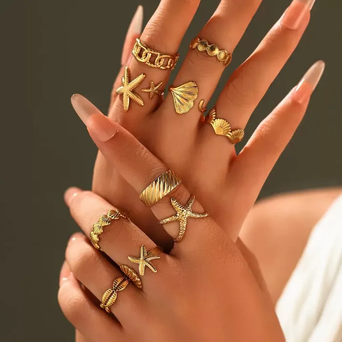 Gold ocean starfish shell rings set with seashell, starfish, chain and textured open ring designs shown on hand for wholesale jewelry buyers